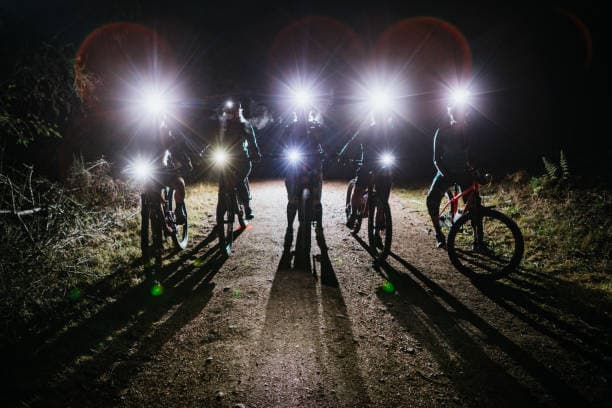 Un grupo de ciclistas con luces encendidas de noche